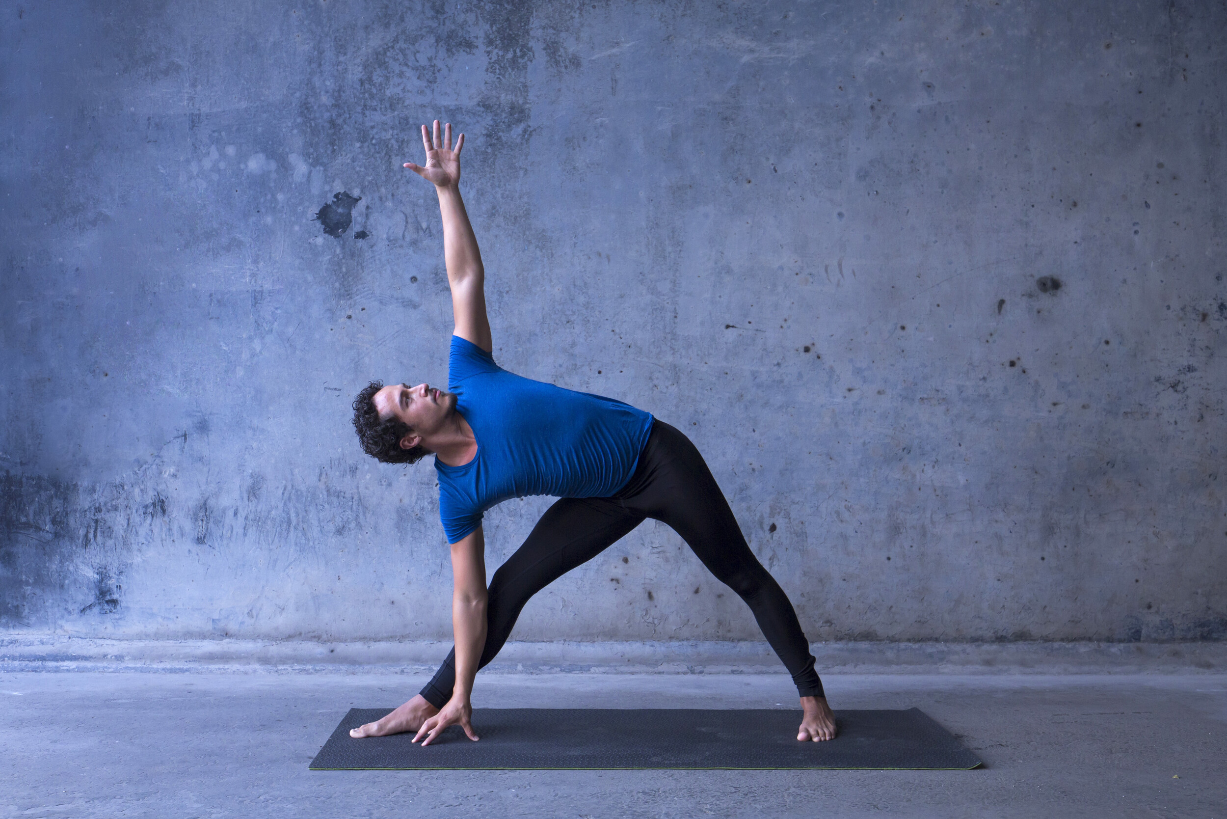 Ein junger Yoga Praktizierender zeigt die Trikonasana